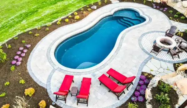 free form pool in a beautifull dark grey color view from above with grey pavers all around and sone lounge chair next to the pool